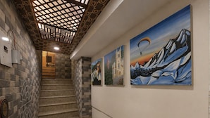 A staircase with a patterned wall and artwork depicting mountains and a parachute.