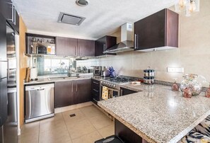 Enjoy cooking in this well-equipped kitchen with a dishwasher, oven, stove, sink, and range hood.