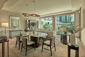 A modern dining area with a glass table, chairs, and a large window offering a view of the city.