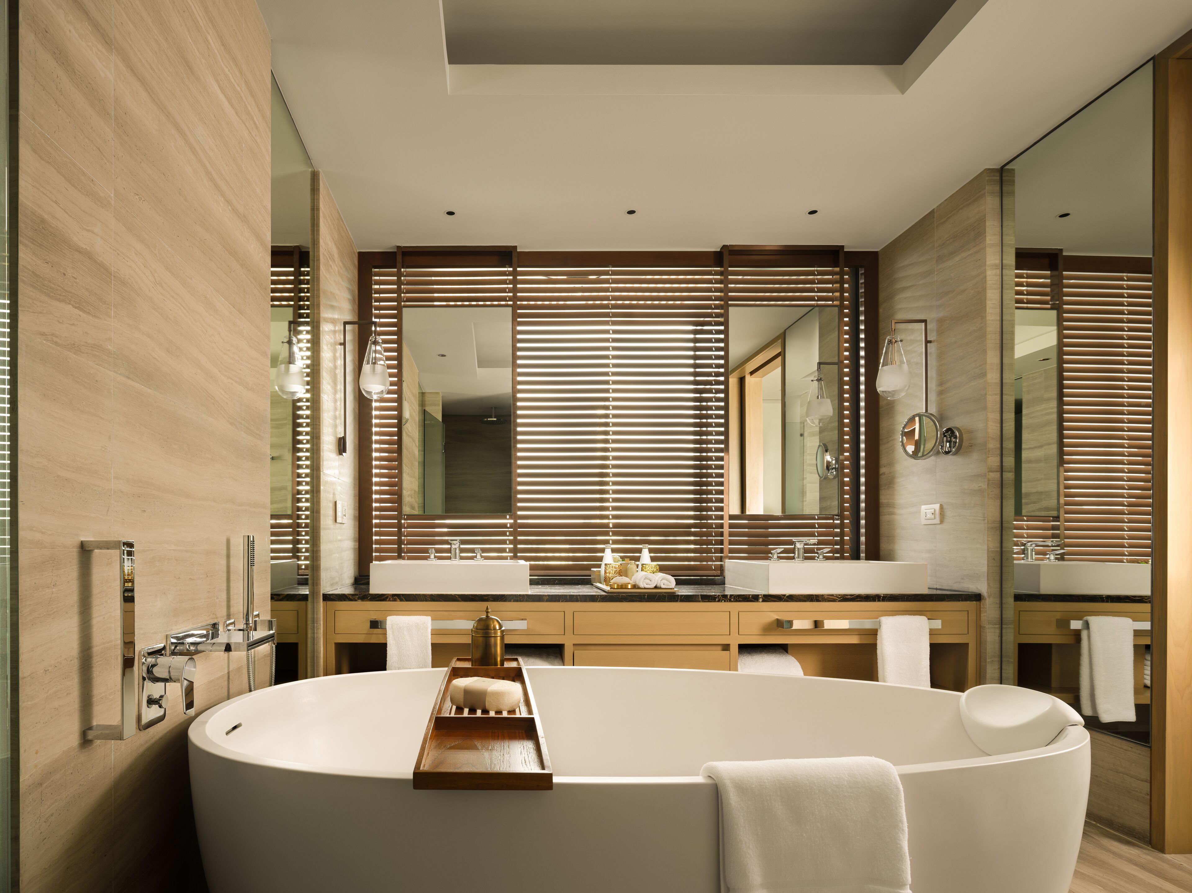 A modern bathroom with a freestanding bathtub, dual sinks, and a large mirror.