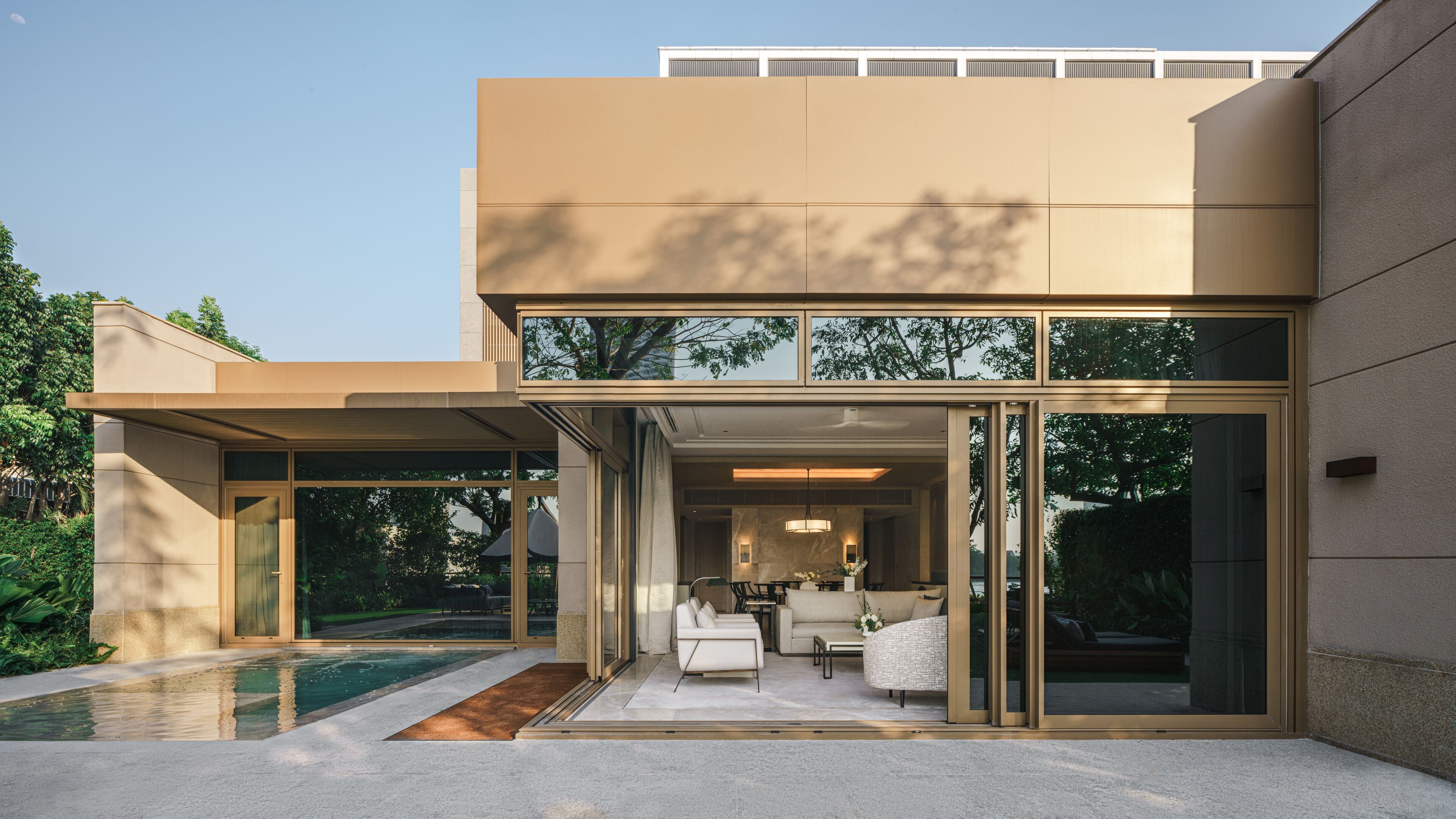 A modern house with a pool, glass doors, and a living area with a sofa and table.