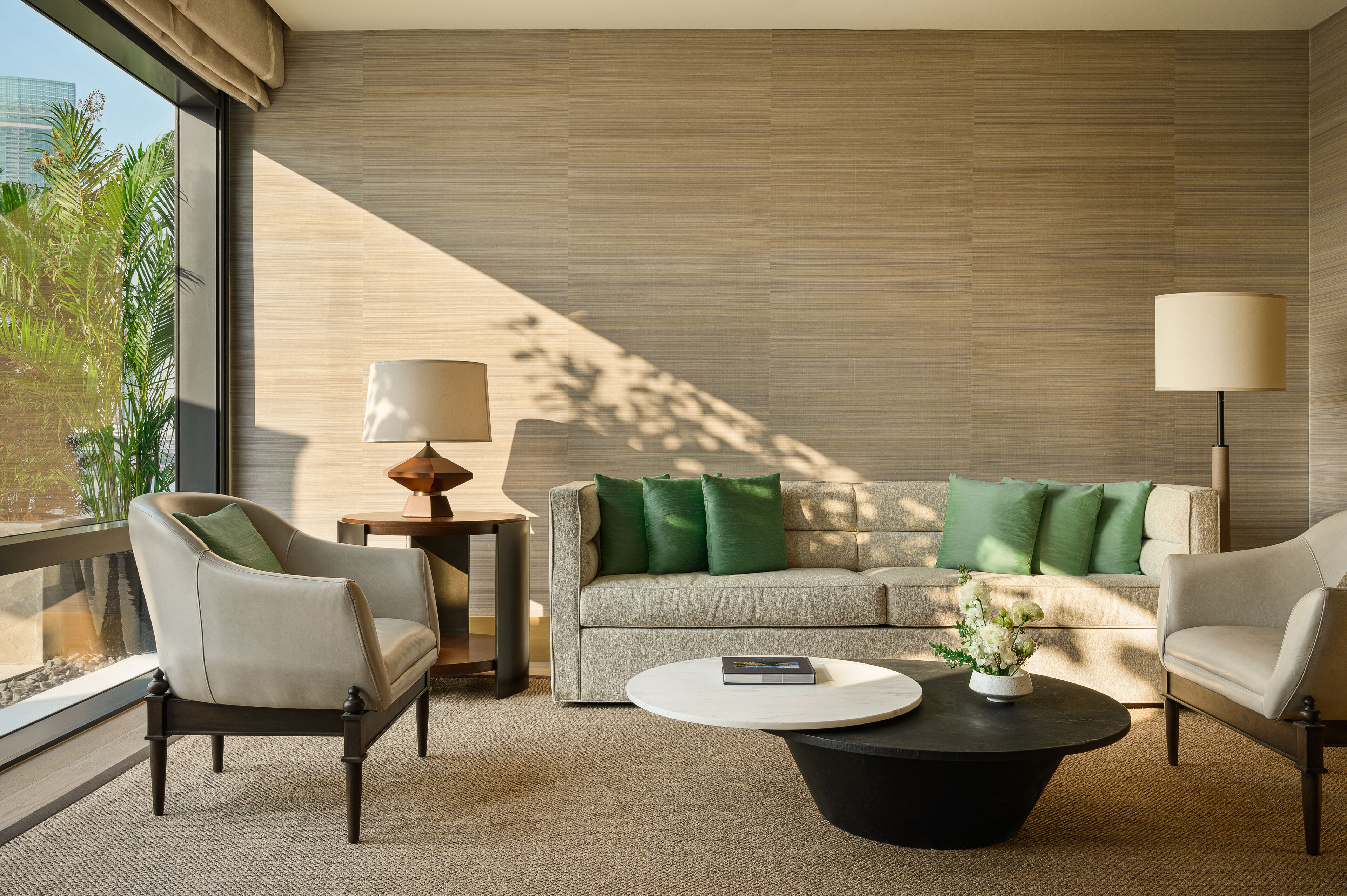 A modern living room with a sofa, two armchairs, a coffee table, and a lamp.