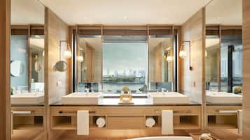 A modern bathroom with dual sinks, large mirrors, and a view of a cityscape.