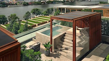 A rooftop terrace with a pool, outdoor seating, and a view of the city skyline across a river.