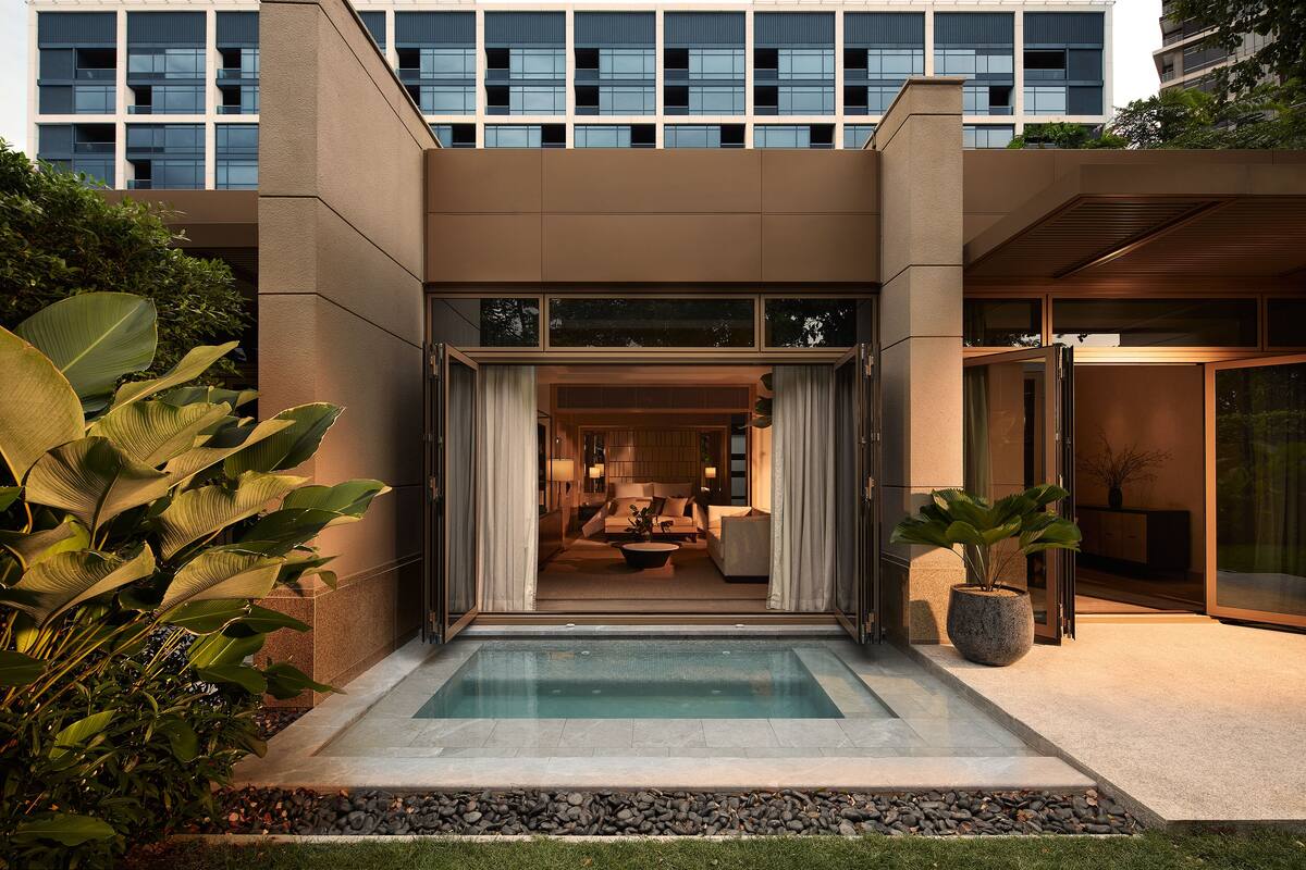 A modern building with a pool, large windows, and a well-maintained garden.
