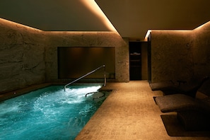 A spa area with a hot tub, seating, and a wall with a textured pattern.