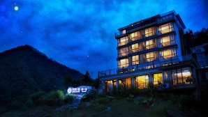 A multi-story hotel with a balcony on the second floor, surrounded by a mountainous landscape. - Floral Hotel Qiandaohu Deyishe Inn (Hangzhou)