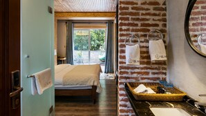 A hotel room with a bed, a wooden ceiling, a brick wall, a bathroom with a mirror, and a window with curtains. - Floral Hotel Hangzhou Nuanshuyiju (Hangzhou)