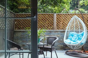 A patio area with wicker chairs, a hanging chair, and a table. - Floral Hotel Hangzhou Nuanshuyiju (Hangzhou)