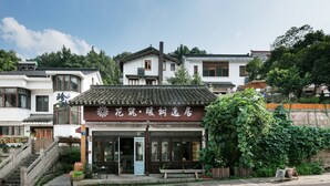A traditional Chinese building with a tiled roof, a wooden staircase, and a signboard. - Floral Hotel Hangzhou Nuanshuyiju (Hangzhou)