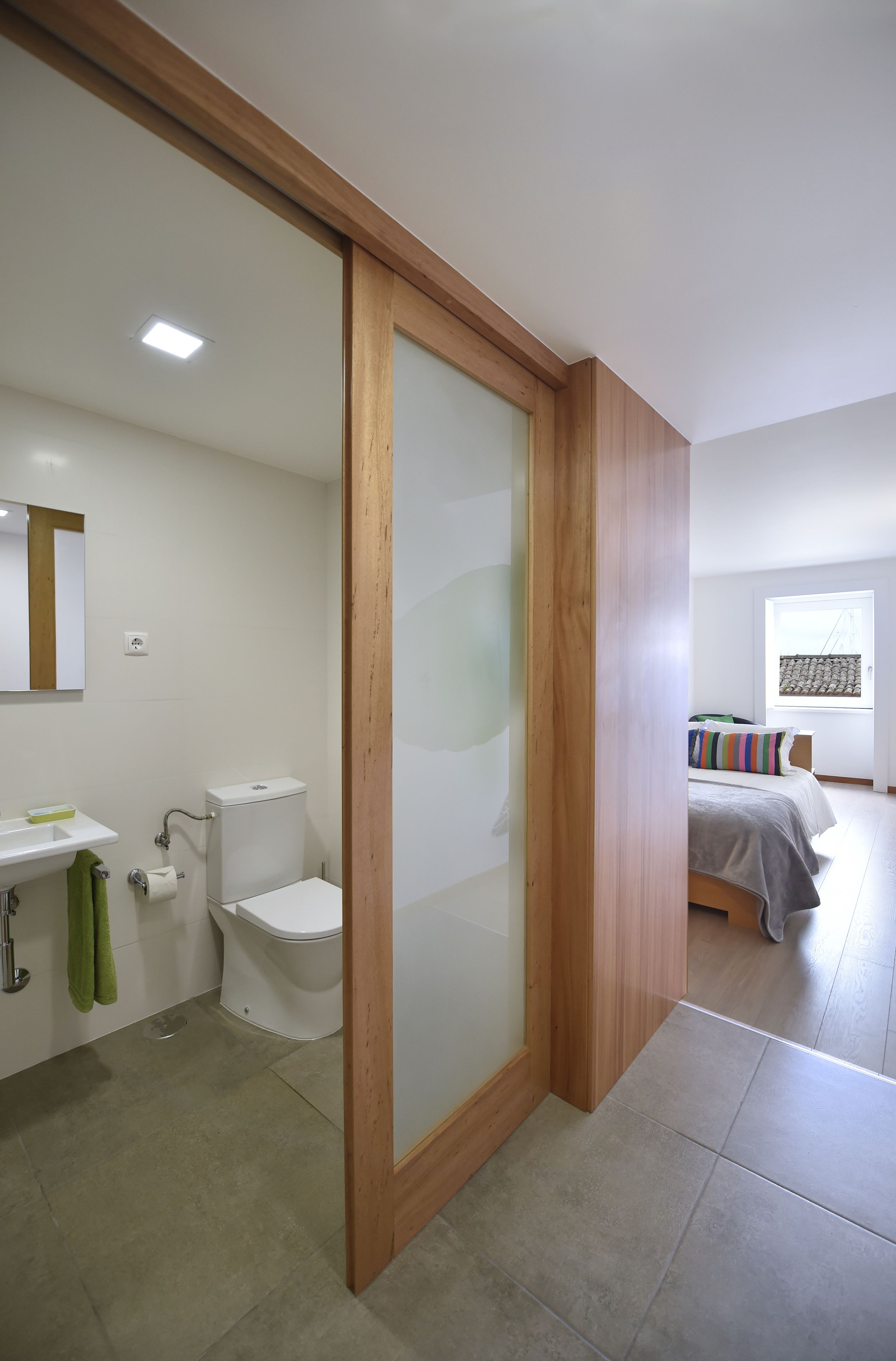 Een moderne badkamer met toilet, wastafel en een deur met houten frame.