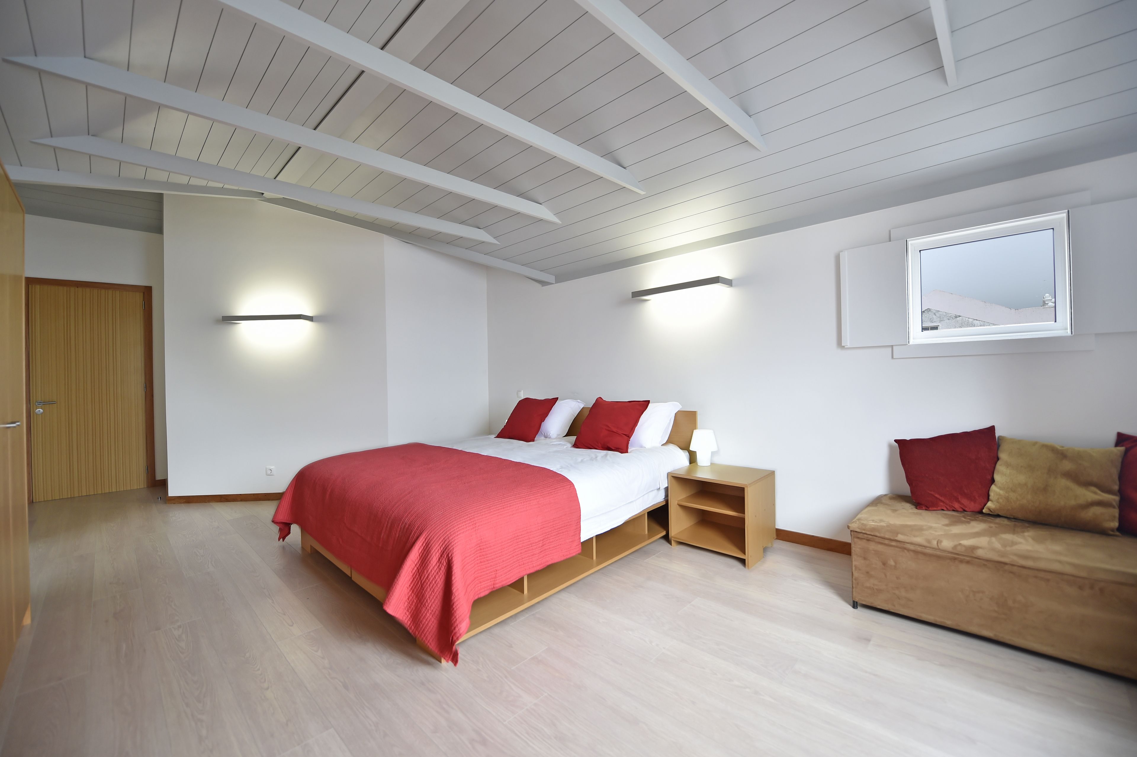 A bedroom with a bed, bedside table, and a sofa.