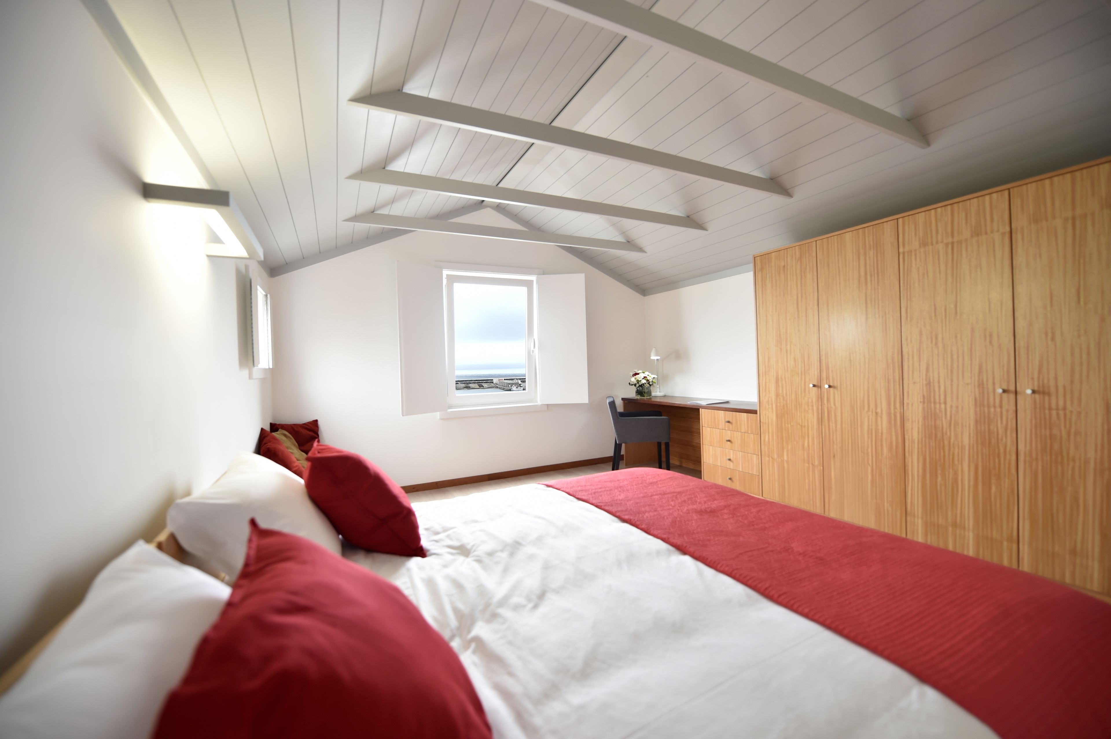 A bedroom with a bed, a desk, and a wardrobe.
