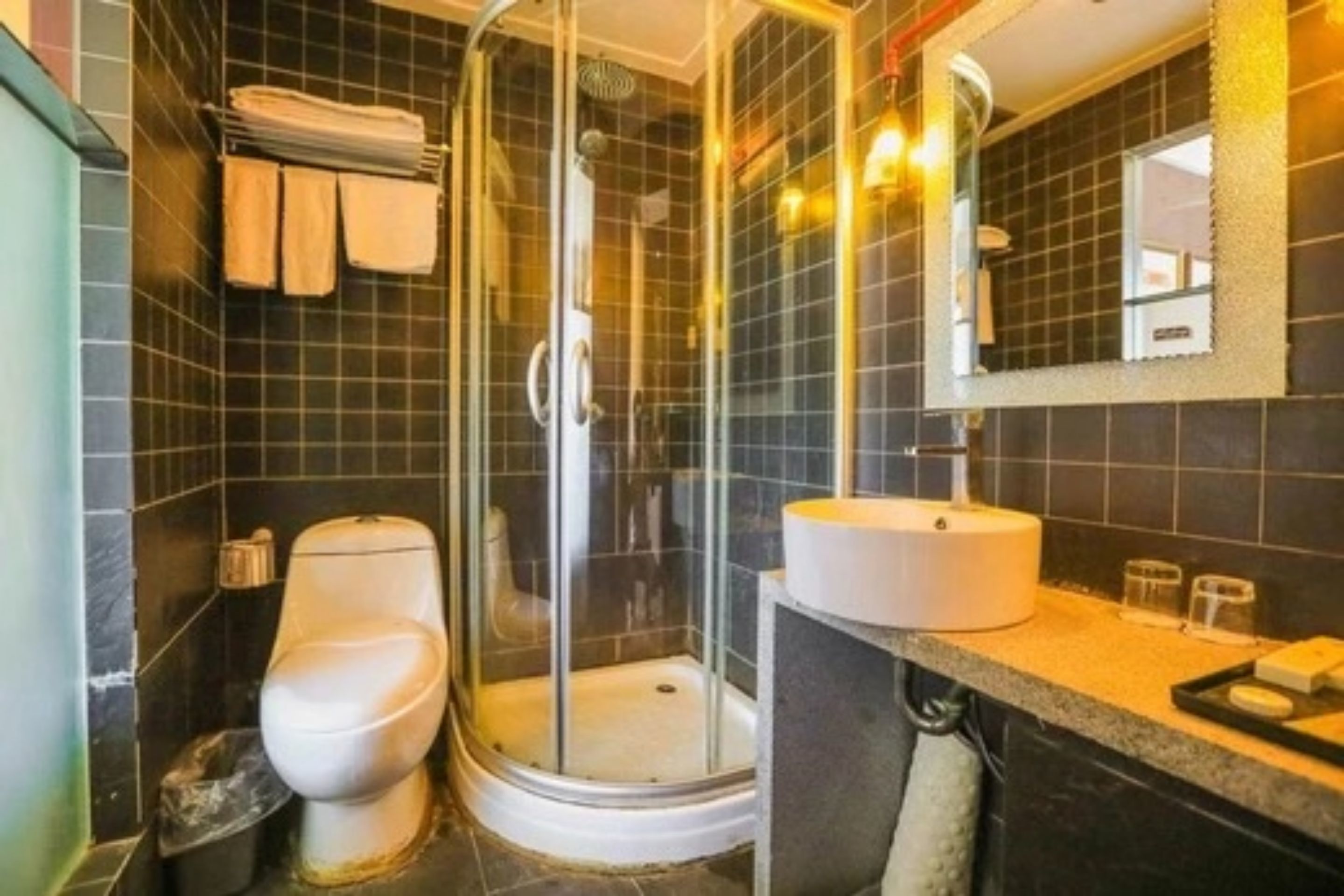 Un baño con ducha de vidrio, inodoro y lavamanos con espejo.