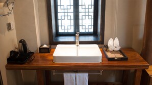 A bathroom with a wooden vanity, a white sink, and a window with a geometric pattern. - Floral Hotel Hangzhou Jiulinjingshe (Hangzhou)