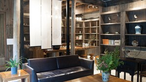 A cozy living area with a leather sofa, wooden coffee table, and a bookshelf filled with books and decorative items. - Floral Hotel Hangzhou Jiulinjingshe (Hangzhou)