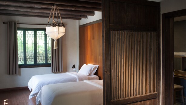 A hotel room with two beds, a wooden door, and a hanging light fixture. - Floral Hotel Hangzhou Jiulinjingshe (Hangzhou)