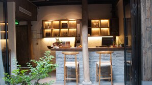 A modern bar area with wooden stools, a brick counter, and ambient lighting. - Floral Hotel Hangzhou Jiulinjingshe (Hangzhou)