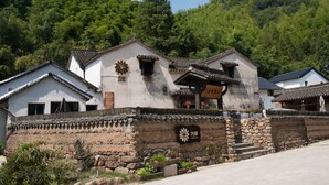 A traditional building with a stone wall, a flower emblem, and a sign. - Floral Hotel Hangzhou Jiulinjingshe (Hangzhou)