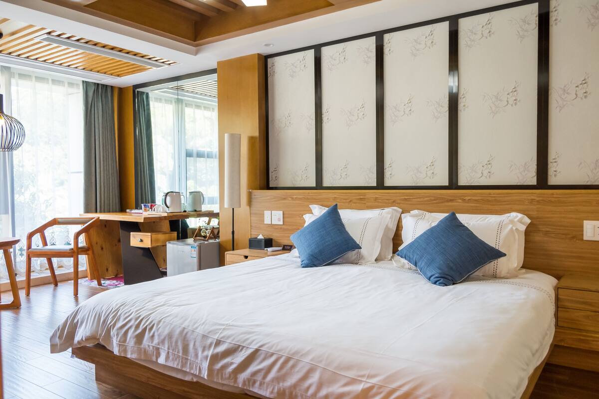 A hotel room with a large bed, a desk, and a chair.