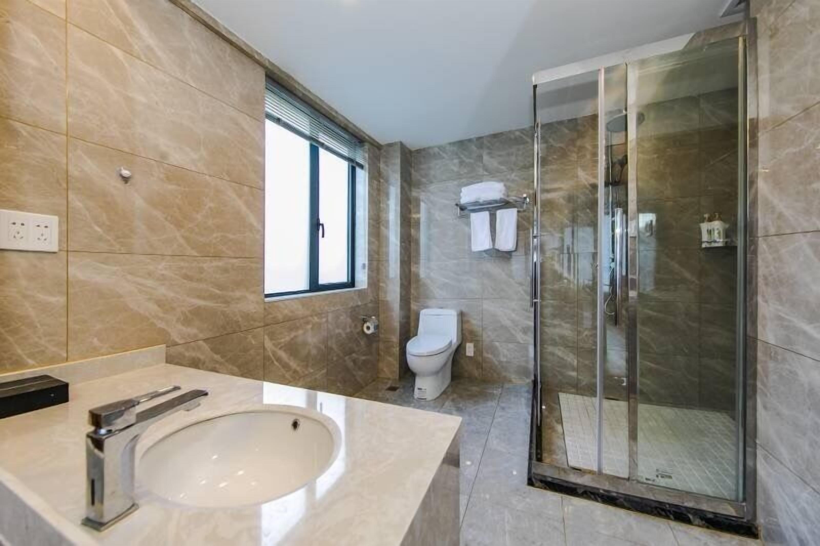 A modern bathroom with a marble sink, a glass-enclosed shower, and a toilet.