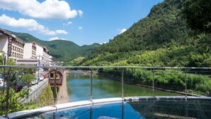 A riverside hotel with a view of a river, surrounded by lush greenery and hills. - Floral Hotel Hangzhou Muxixiaolu (Hangzhou)
