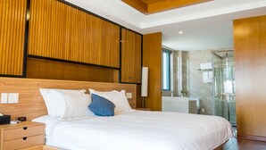 A modern hotel room with a wooden headboard, a large bed with white and blue bedding, a bedside table, and a glass shower area. - Floral Hotel Hangzhou Muxixiaolu (Hangzhou)