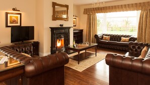 A living room with a fireplace, leather sofas, a coffee table, and a television.