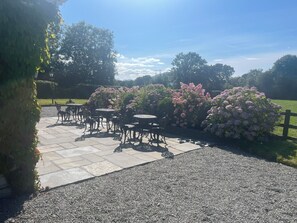 An outdoor patio area with stone flooring and metal tables and chairs.