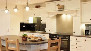 A modern kitchen with a central island, built-in oven, and a coffee maker.