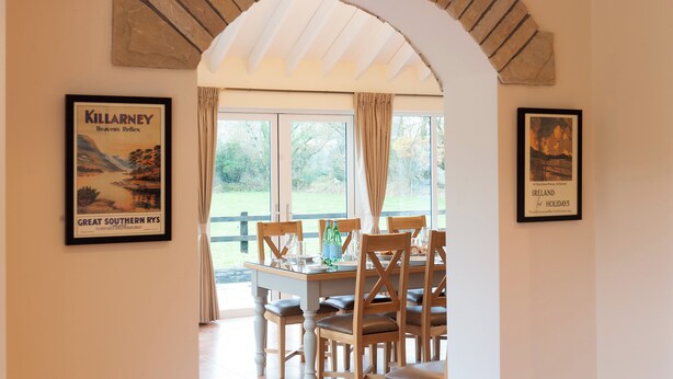 A dining area with a table set for four, framed posters on the walls, and a view of the outdoors.