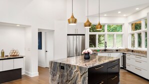 Una cocina moderna con una isla de mármol, electrodomésticos de acero inoxidable e iluminación colgante.
