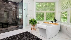 Un baño moderno con una bañera independiente, cabina de ducha con paredes de vidrio y un ventanal con persianas verdes.