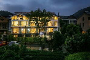 A multi-story hotel with a balcony, surrounded by greenery and parked cars. - Floral Hotel Hangzhou Yunqi Fanjinglan (Hangzhou)