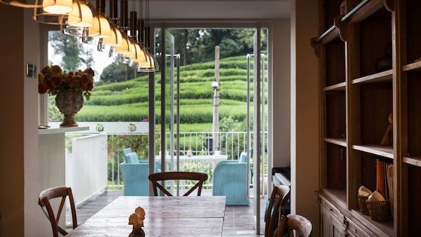 A dining area with a wooden table, chairs, and a vase of flowers. There is a view of a garden through a glass door. - Floral Hotel Hangzhou Yunqi Fanjinglan (Hangzhou)