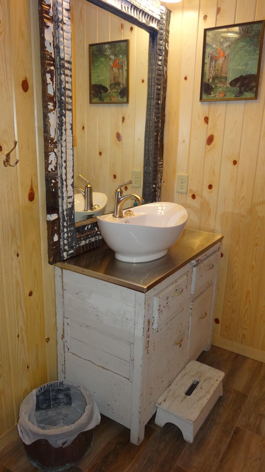 Un baño con un lavamanos blanco, dos espejos y paredes de madera.