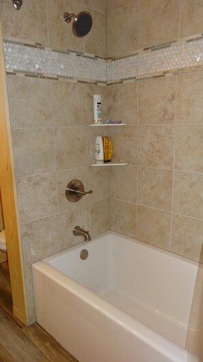 Een bad/douchecombinatie, handdoeken, zeep, shampoo
