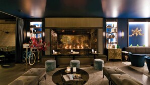 A modern living room with a fireplace, seating, and a bicycle. - Hotel AMO by AMANO Friedrichstraße (Berlin)