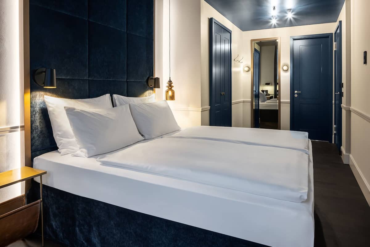 Una habitación de hotel con una cama grande, un cabecero oscuro y un espejo en la pared.