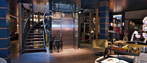 Un moderno vestíbulo de hotel con una escalera en espiral, una recepción y un área de descanso.