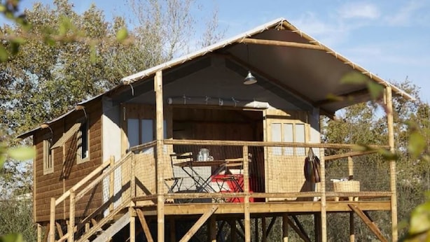 A wooden cabin with a balcony, a covered porch, and a staircase leading to the entrance.