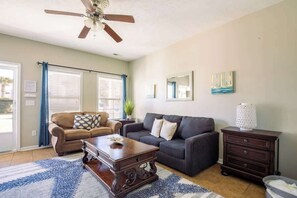 A living room with a ceiling fan, two sofas, a coffee table, a side table, and a lamp.