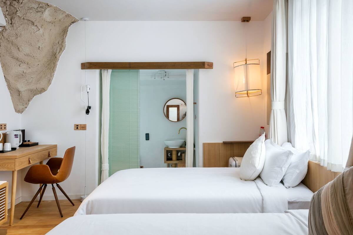 Une chambre d’hôtel avec un lit, un bureau, une chaise, un lavabo et un miroir.