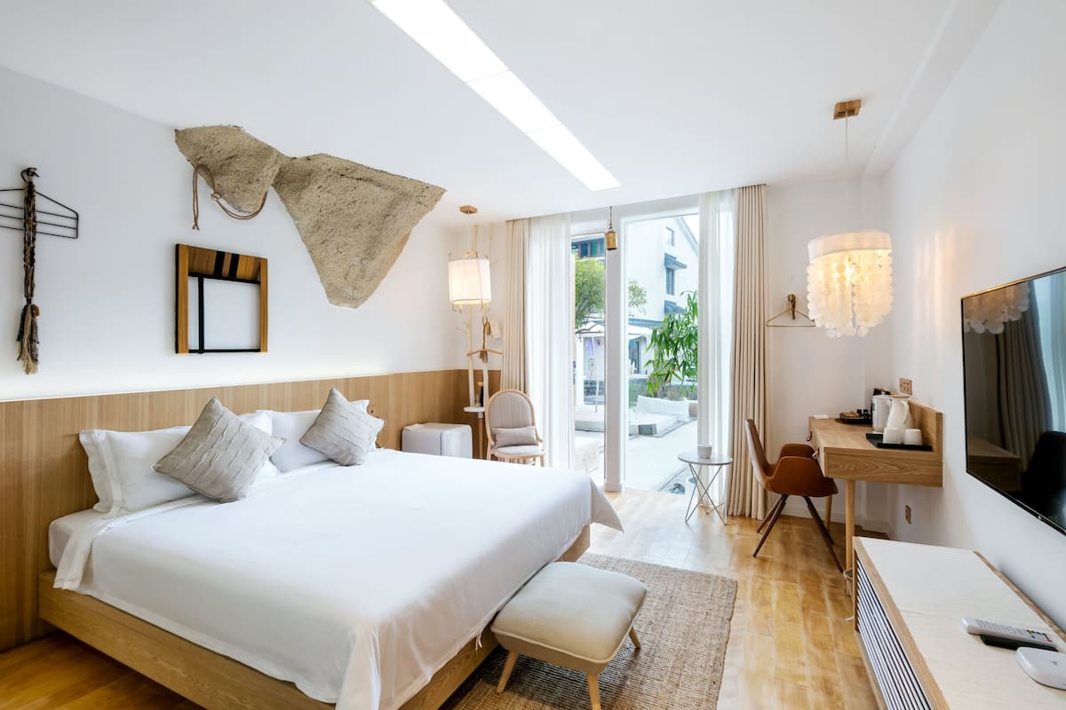 Une chambre d’hôtel avec un grand lit, un bureau, une télévision et une vue sur l’extérieur.