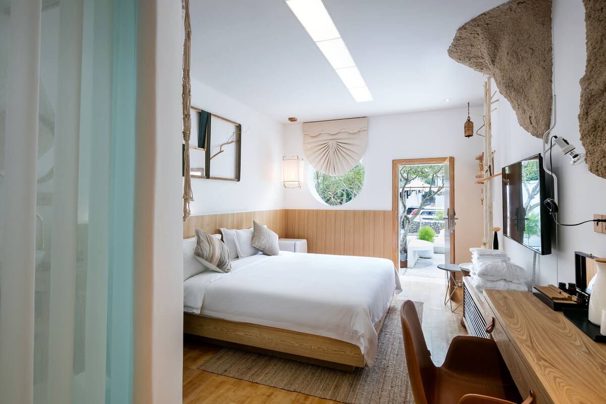 Une chambre à coucher moderne avec un lit en bois, un bureau et un téléviseur.