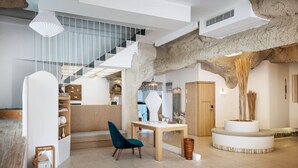 A spacious living area with a staircase, a round table, and a blue chair. - Floral Hotel Hangzhou Lvpin Designer (Hangzhou)