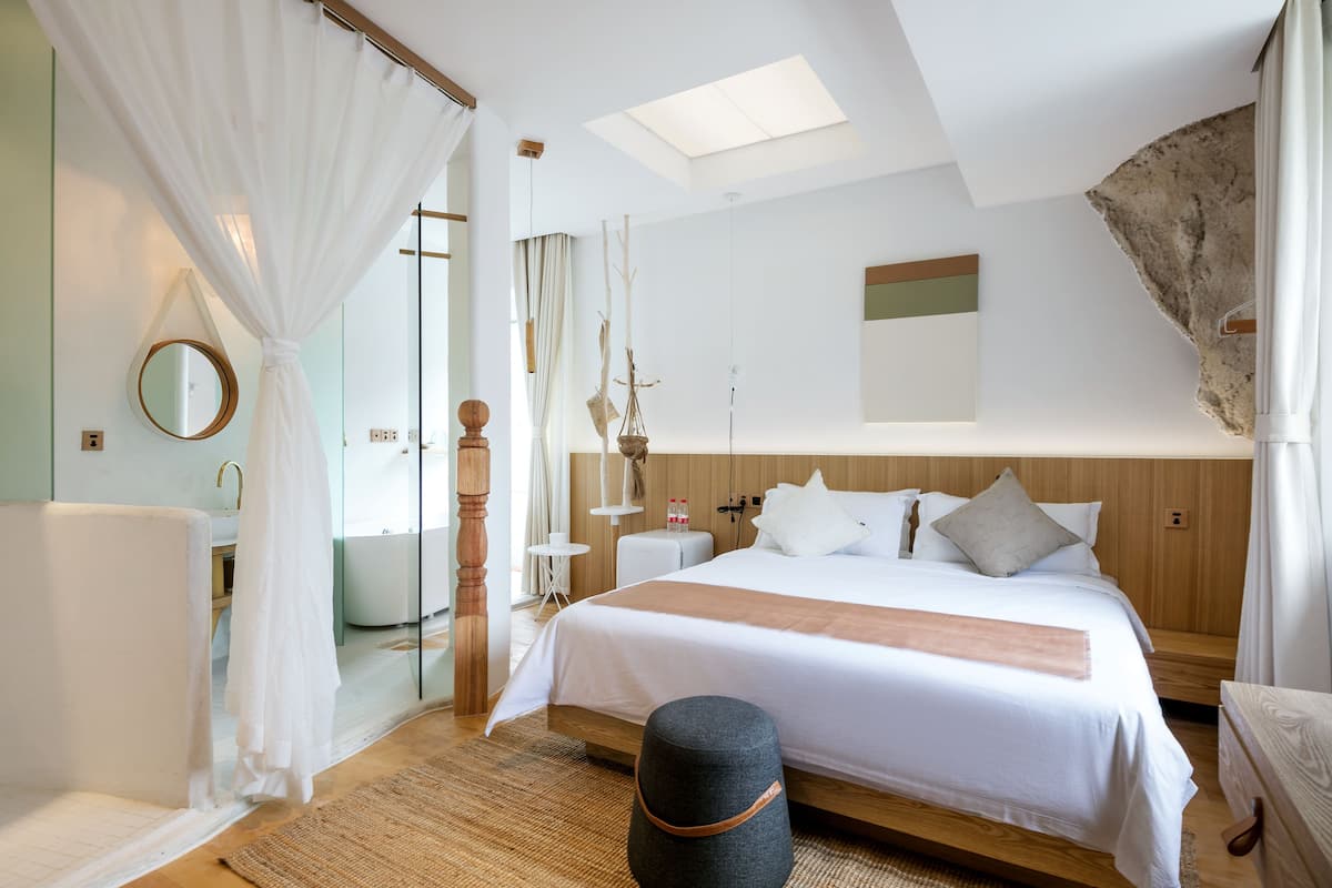 Une chambre d’hôtel moderne dotée d’un grand lit, d’un coin salon et d’une salle de bain.