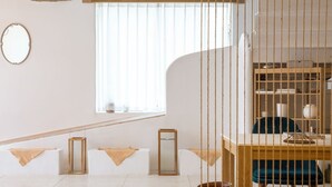 A modern room with a wooden desk, a chair, a small table, and a window with blinds. - Floral Hotel Hangzhou Lvpin Designer (Hangzhou)
