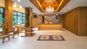 A reception area with a wooden reception desk, a chandelier, and a seating area with a sofa and chairs. - Andaman Breeze Resort - (Krabi)