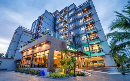 A multi-story hotel with a modern design, featuring balconies, large windows, and a well-lit entrance.